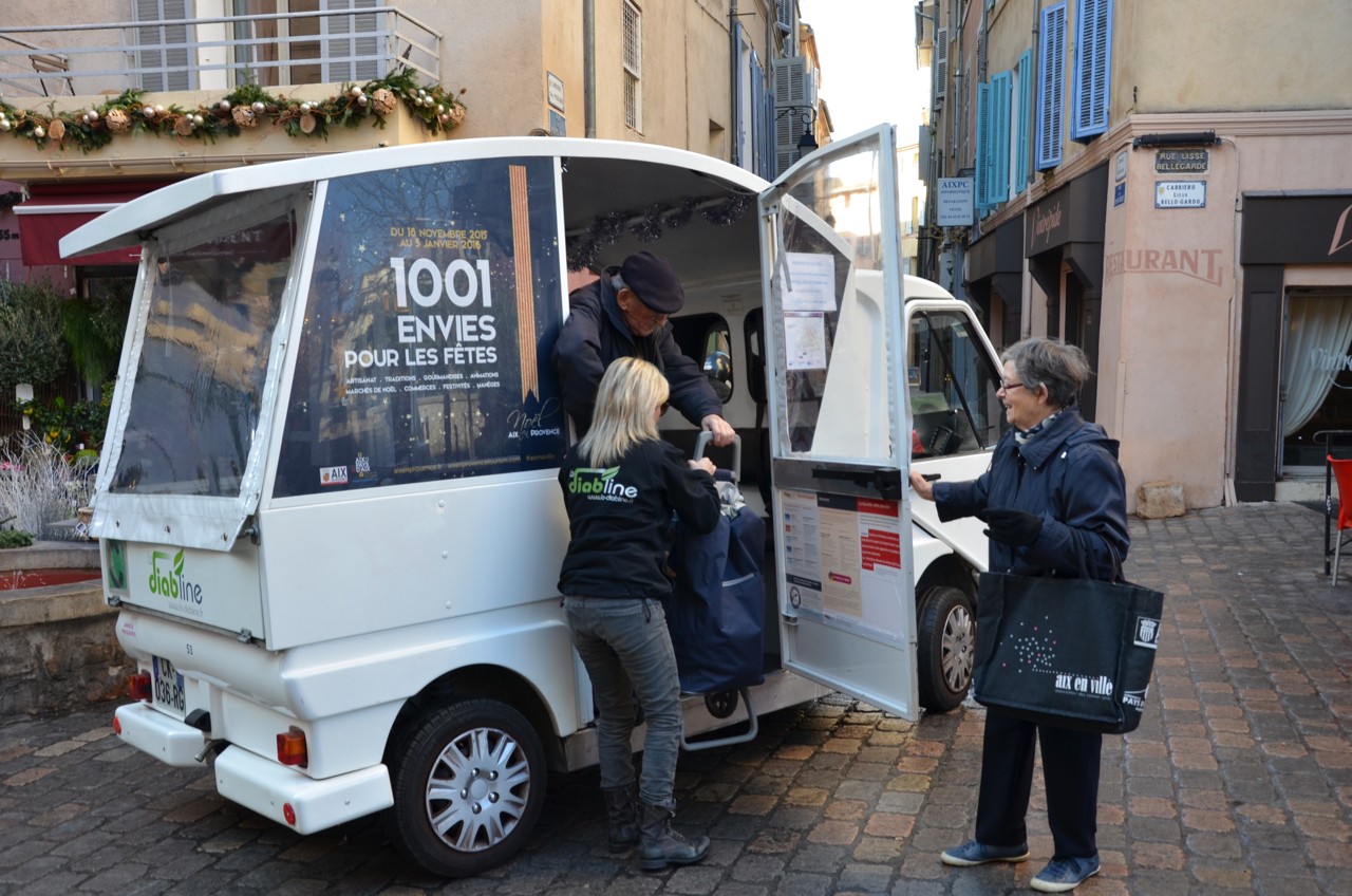 Navette électrique Diabline dans une rue d'Aix-en-Provence, une passagère aidée à monter à bord