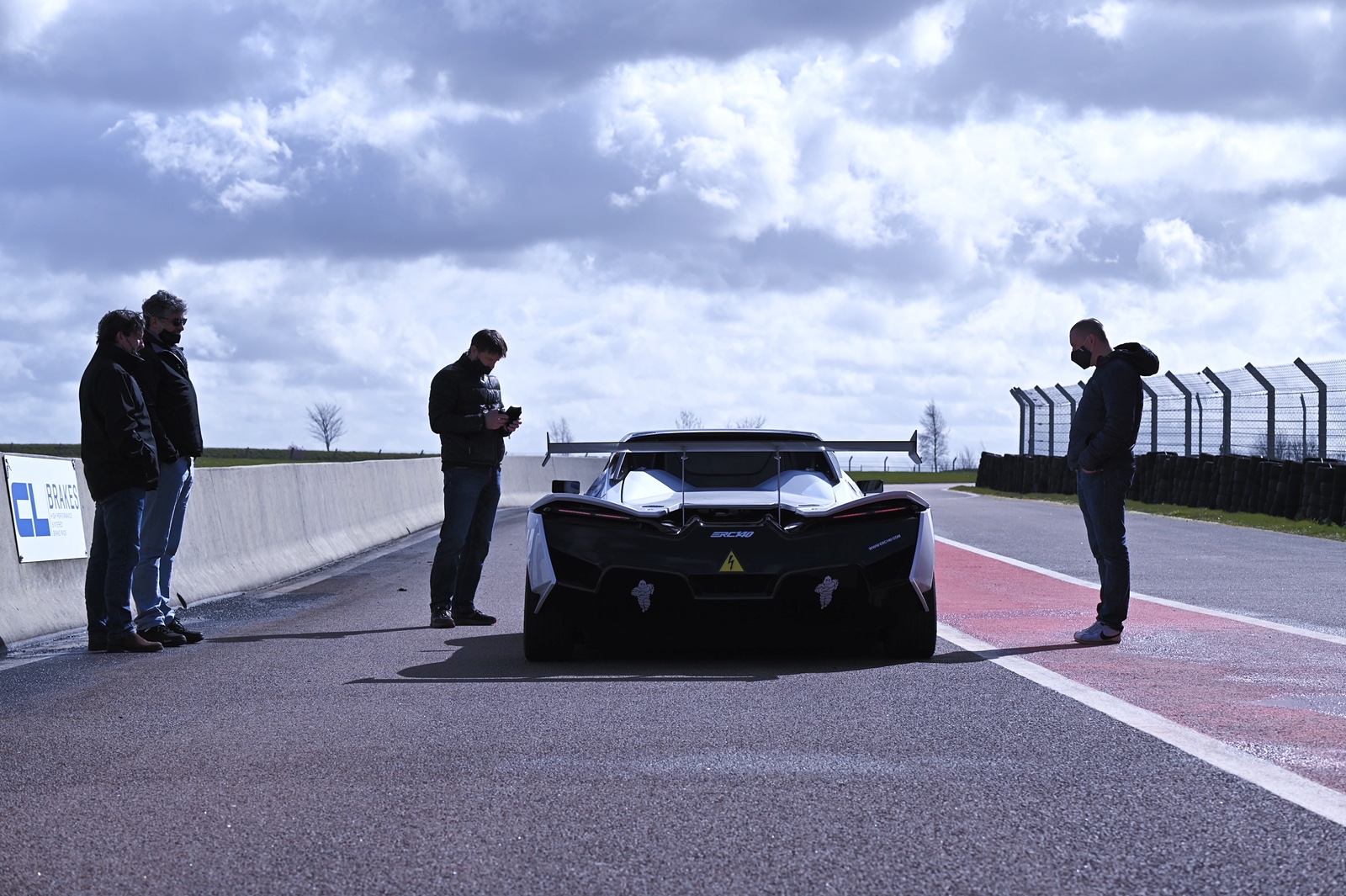 L'eCup 200 à l'arrêt sur un circuit, vue de l'arrière, entourée de l'équipe