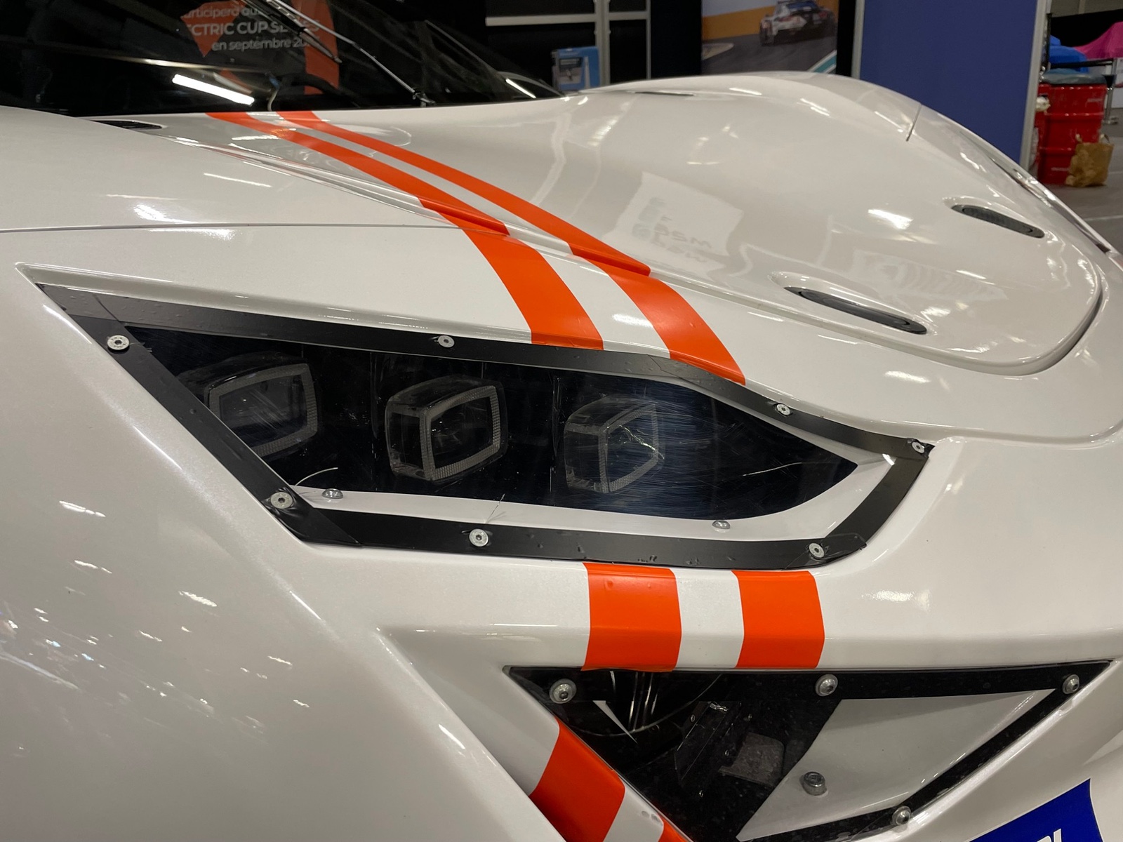 Détail du phare et des bandes orange sur la carrosserie blanche